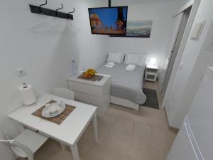 a small white bedroom with a bed and a table at Room Dream Beato in Lisbon