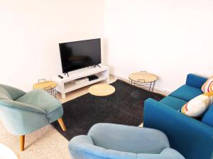 uma sala de estar com duas cadeiras azuis e uma televisão em Grand Appartement Ensoleillé avec Parking em Nîmes