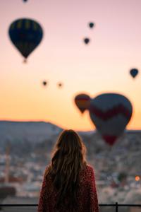 a woman is looking at a bunch of hot air balloons at Perla Cappadocia in Goreme