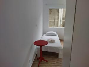 um pequeno quarto com uma pequena cama e uma mesa vermelha em RESIDENCIAL BOTÂNICO em Curitiba