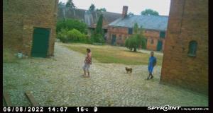 two people and a dog walking in a yard at Bauernhof-Streichel-Zoo-&-Reiter-Suite in Gulow