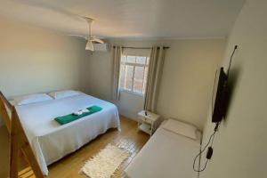 Schlafzimmer mit einem weißen Bett und einem Flachbild-TV in der Unterkunft Pousada do beco in Caravelas