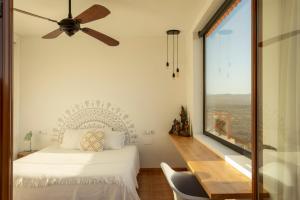 a bedroom with a bed and a table and a window at Villa Calderón Hondo. Top design , views and pool Lajares-Corralejo in Corralejo