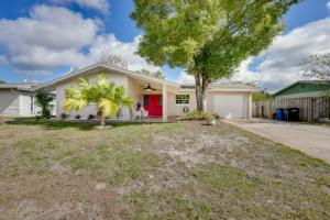 a house with a red door and a tree at Clearwater Vacation Home Rental with Tiki Bar! in Clearwater