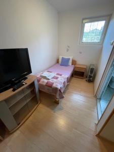 een kleine kamer met een bed en een flatscreen-tv bij Guest House Luxotel in Zrenjanin