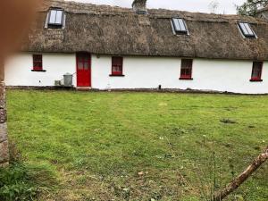 RooskeyにあるSweet Meadow A delightful romantic thatched cottage by river Shannon on 4 acres is for peace party family or work from homeの茅葺き屋根の白い家