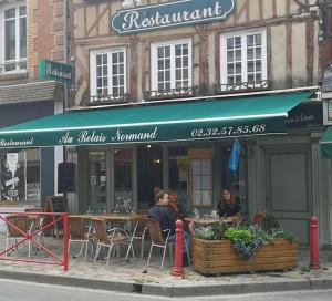 duas pessoas sentadas numa mesa fora de um restaurante em Chambre indépendante Au Relais Normand em Cormeilles