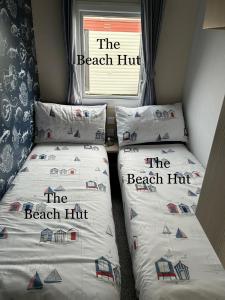 two twin beds in a room with the beach hit at Lyons Robin Hood, RHYL "The Beach Hut" in Rhyl
