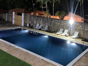 uma piscina à noite com cadeiras à volta em Pousada o Amanhecer em Tiradentes