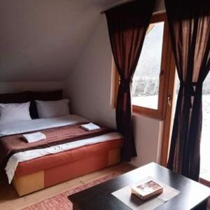 - une chambre avec un lit, une table et une fenêtre dans l'établissement Vikend kuća Đoković - Jahorina, à Pale