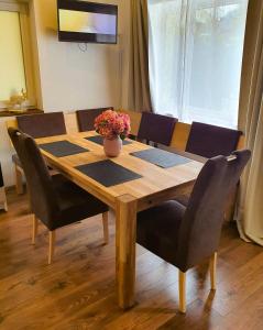 a wooden table with chairs and a vase of flowers on it at Kozma Apartments Peterlewand in Bodensdorf