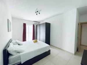 a bedroom with a bed with white sheets and a window at Modern St.Julian's Heart 2 Bed 2 Bath | Paceville in St. Julianʼs