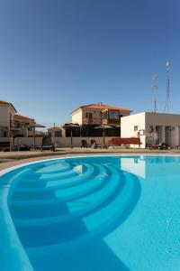 a large blue swimming pool in front of a building at Villa Calderón Hondo. Top design , views and pool Lajares-Corralejo in Corralejo