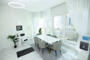 a white dining room with a table and chairs at New Sunny spacious 2BR beach viewApt in Sharjah