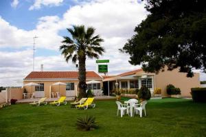 a building with tables and chairs and a palm tree at VILA FORMOSA AL-Estabelecimento de Hospedagem,Quartos-Rooms in Monte Gordo