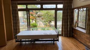 a bed in a room with a large window at 旅する人生ハウス鹿屋 in Kanoya