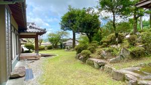 a garden with rocks and bushes next to a house at 旅する人生ハウス鹿屋 in Kanoya