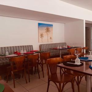 a restaurant with tables and chairs and a painting of palm trees at Apartamento Reserva do Sahy - Condomínio Aldeia dos Reis in Mangaratiba