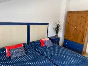 1 dormitorio con cama azul y almohadas rojas en ISLA, APARTAMENTO con PISCINA, en Isla