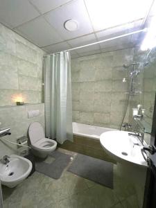 a bathroom with a toilet and a sink and a tub at Beach view, Cozy 2BR apartment in Sharjah