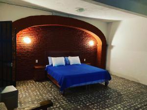a bedroom with a blue bed with a brick wall at EL GRAN TORIL in Taxco de Alarcón