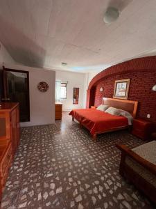 a bedroom with a red bed and a brick wall at EL GRAN TORIL in Taxco de Alarcón