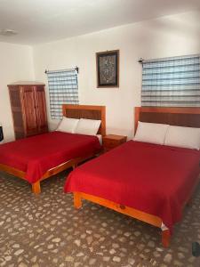 two beds with red sheets in a room at EL GRAN TORIL in Taxco de Alarcón