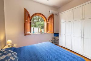 a bedroom with a blue bed and a window at 3-Casa sul mare con piscina vicino Cefalù in Campofelice di Roccella