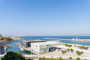 un gran edificio blanco junto a una masa de agua en Marseille: appartement standing vue sur mer, en Marsella