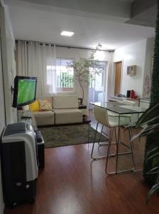 a living room with a tv and a table and a couch at APTO COM VARANDA - 5KM DO AEROPORTO BSB - Nucleo Bandeirante in Brasilia