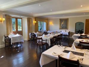 a dining room with tables and chairs with white linens at Plumber Manor Hotel in Sturminster Newton