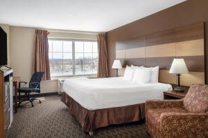 a hotel room with a bed and a chair at AmericInn by Wyndham Cedar Rapids North in Cedar Rapids