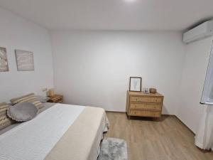 een witte slaapkamer met een bed en een houten dressoir bij Rinconcito en el almendral in Jaén