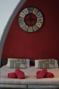 a clock on the wall above a bed with red pillows at Estudi Suite Desvern in Sant Just Desvern