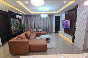 a living room with a brown couch and a tv at Jay's Luxury Condo in Lekki