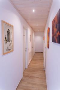 un corridoio con pareti bianche, pavimenti in parquet e dipinti di Affittacamere Ceccarini a Riccione