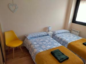 a bedroom with two beds and a yellow chair at El Mirador del Valle, a 9 min de Comillas in Comillas