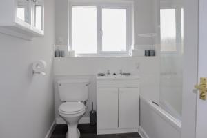 a white bathroom with a toilet and a sink at Wester-Moor comfy modern house in Barnstaple by StayStay com in Barnstaple