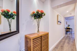 two vases of flowers on a wooden cabinet in a hallway at Beautiful One Bedroom Apartment in Brentwood