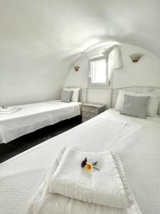 two beds in a white room with a flower on thevisor at Alonistra Oia Houses in Oia