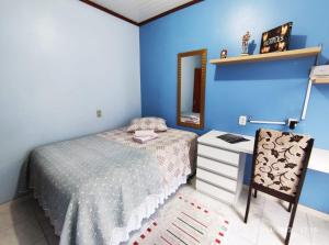 a bedroom with blue walls and a bed and a chair at Quarto, piscina e acesso exclusivo in Encantado