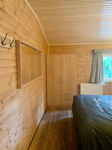 ein Schlafzimmer mit Holzwänden und ein Bett in einem Zimmer in der Unterkunft Het Zenhuisje in Lanaken