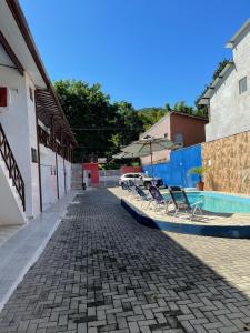 un patio con sillas y una sombrilla junto a la piscina en Pousada Canto Juquehy en Juquei