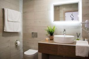 a bathroom with a sink and a toilet and a mirror at Big Max Guesthouse in Kavos