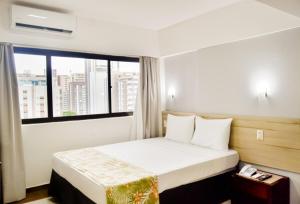 a bedroom with a bed with a large window at Aram Beach Boa Viagem in Recife