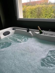 a bath tub with a bottle of champagne in it at Le Refuge des Etoiles Gîte et Spa in Zutkerque