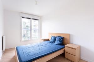um quarto com uma cama com lençóis azuis e uma janela em Apart neuf quartier sympa em Bois-Colombes