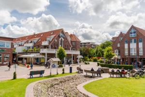 a town square with buildings and people sitting on benches at Hotel Leuchtfeuer in Horumersiel