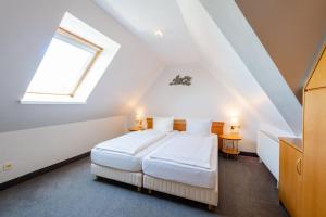 a bedroom with a white bed in a attic at Hotel Leuchtfeuer in Horumersiel