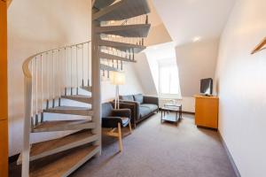 a living room with a spiral staircase and a couch at Hotel Leuchtfeuer in Horumersiel